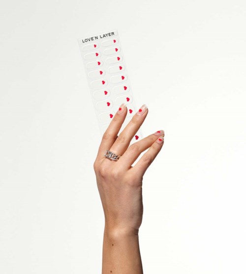 En hand med ett ring håller ett papper med röda hjärtan i fyra kolumner, märkt "LOVE N LAYER."