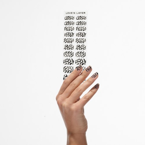 A hand holds a strip with black wavy lines, numbered 'LOVE N LAYER' at the top, on a white background.