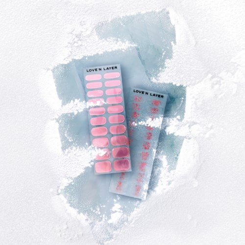 Två blad med rosa nagelklistermärken på snötäckta ytan, märkta "Loven Layer."