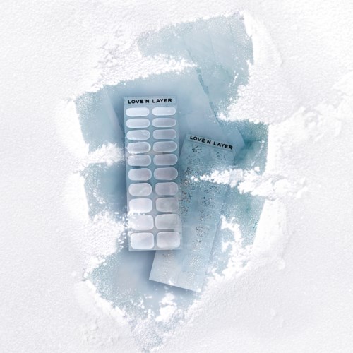 Två blå förpackningar med limremsor märkta "Loven Layer" på snö med snöspray.