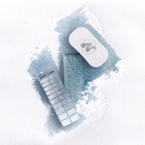 Ett hudvårdsprodukter inklusive en vit behållare, ett band av lappar och en liten broschyr, alla på snö.