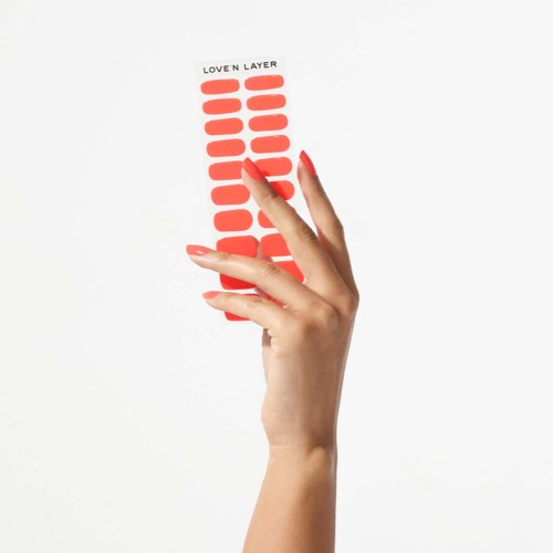A hand holds a strip of red nail polish color samples labeled "Lover Layer."