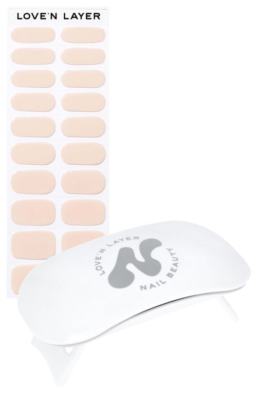 Ett set nagelklistermärken i beige färg och en vit nagelvårdsanordning med en logotyp. Klistermärkena är ordnade i rader.