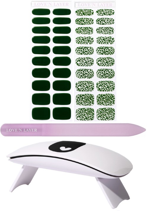 Nagellacksstickers med solid gröna och mönstrade designer, en rosa UV-lampa och en vit nageltork.
