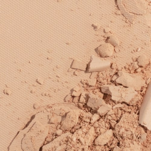 Knuste keramikkstykker spredt på sand, med noen merker og sprekker synlige.