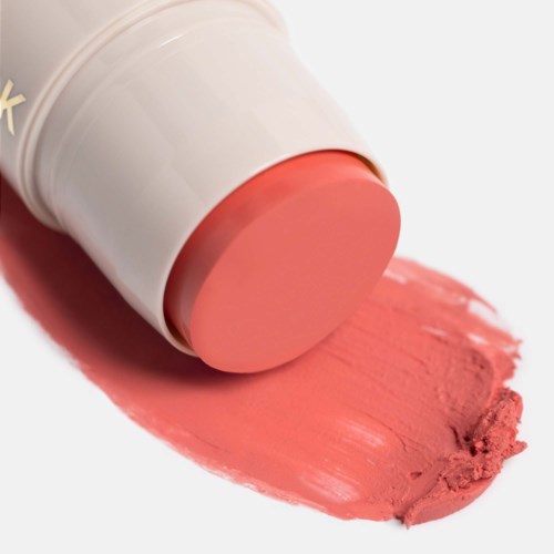 Ett stycke rosa läppstift med lite färg utbredd på en vit bakgrund.
