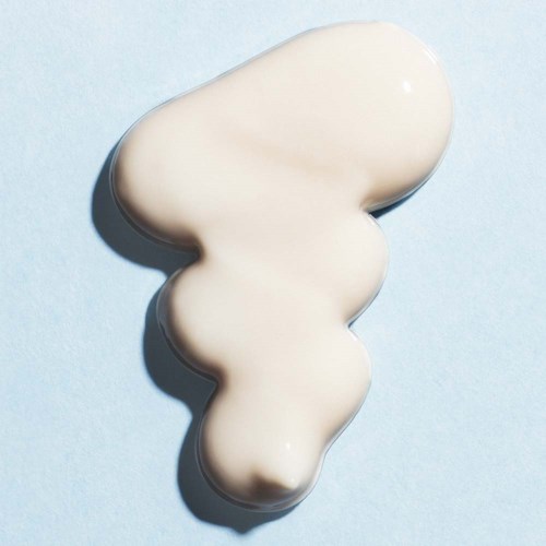 En klat med hvid creme med glat, skinnende tekstur på en lys blå baggrund.
