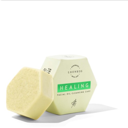 A facial cleansing oil cake in a hexagon shape, with a soap piece beside its box labeled 'Healing.'
