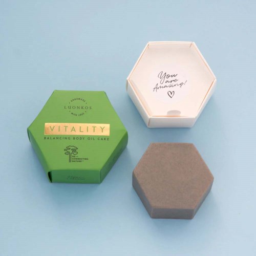 Een groene doos met 'Vitality' erop en een grijze doos liggen op een lichtblauwe ondergrond. Een open witte zeshoekige doos zegt, 'You are Amazing!'