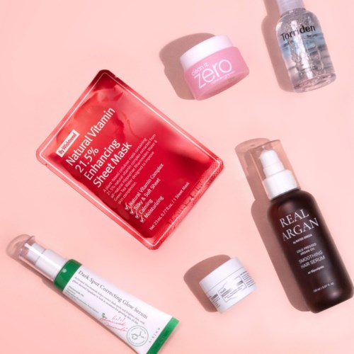 Huidverzorgingsproducten zoals maskers, serums en olieflesjes op roze achtergrond.