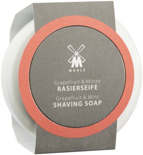 A round container with a gray and pink label for grapefruit and mint shaving soap.