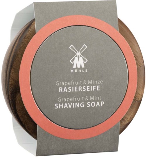 A round wooden container with a grey label and pink border, showing it is grapefruit and mint shaving soap.