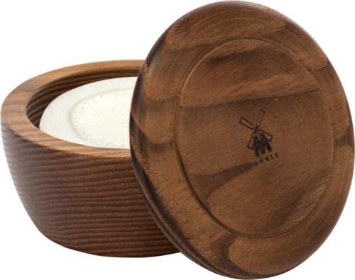 A round wooden container with a lid, holding a white candle inside, and a small logo of a windmill.