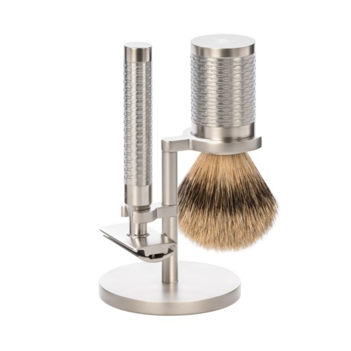 Metalowy stojak na brush do golenia z dwoma pionowymi rurami, jedna trzymająca brush z brązowymi włosami.