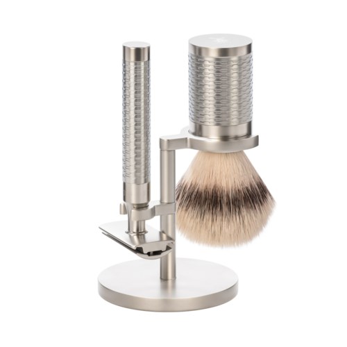 En silver mikrofon med inbyggd hållare och ett stort, fluffigt, beige och svart vindskydd.