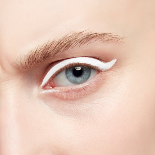 Close-up van een blauw oog met witte eyeliner op het bovenste ooglid en natuurlijke huid.