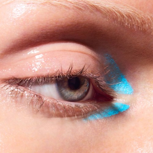 Close-up van een menselijk oog met een streepje heldere blauwe oogschaduw eronder.
