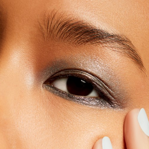 Närbild av ett persons öga med smink, inklusive ögonskugga och eyeliner, samt deras ögonbryn.