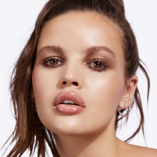A young woman with brown hair and light makeup looks confidently at the camera.