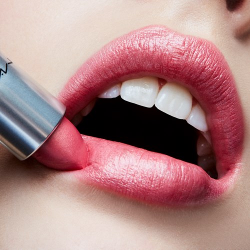 Close-up van lippen met roze lippenstift en persoon die meer lippenstift aanbrengt.