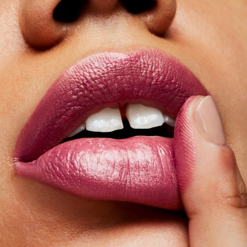 Close-up van lippen die je finger aanraakt, met roze lipstick en witte tanden, huid zichtbaar eromheen. Focus op lippen en vinger.
