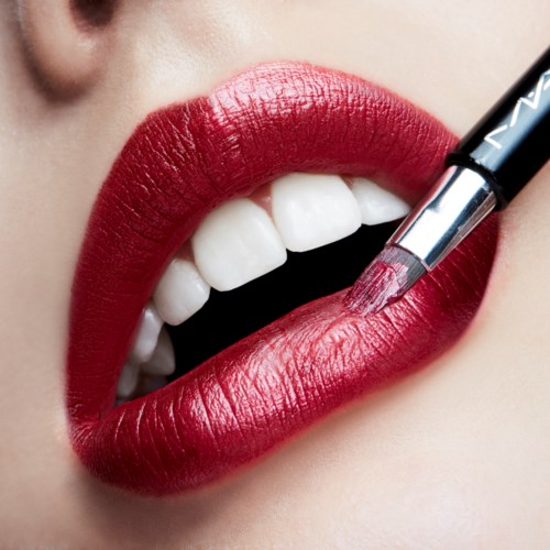 Close-up van lippen die rood lipstick krijgen, witte tanden zichtbaar en een lipstickapplicator wordt gebruikt.