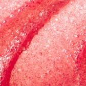 Närbild av en rosa, texturerad frukt- eller matyta med små prickar och en böjd linje.
