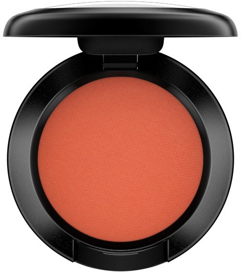 En komp makeup-rouge med aprikos-orange färg i ett svart fodral med lock.