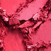 Crushed pink powder, some large pieces, soft texture, vibrant color, on a surface. It looks like makeup or pigment.