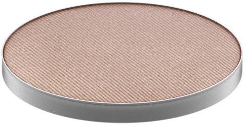 A round, flat makeup highlighter with a light peach color and a textured surface.