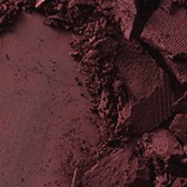 Broken makeup powder in shades of pink and red, scattered in a messy, textured manner.