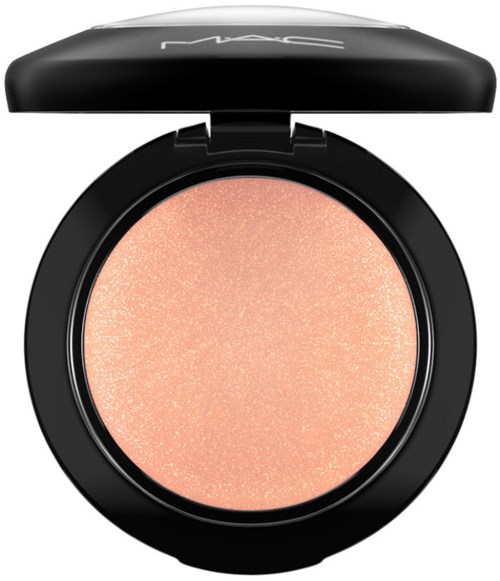 Een ronde make-up compact met een perzikkleurige glanzende poeder en een zwarte deksel met merknaam.
