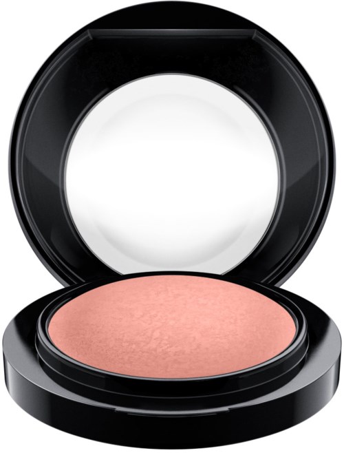 A compact with peach-colored blush inside a black case and an open mirror.