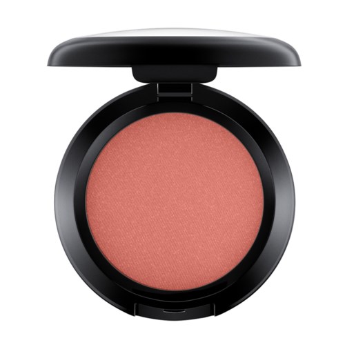A round makeup compact with a blush or powder inside, black lid open, pinkish coral color, creamy texture.