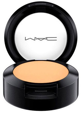 Kompaktowy produkt do makijażu z jasnobeżowym sypkim pudrem w czarnym okrągłym opakowaniu. Logo MAC widoczne na wewnętrznej stronie pokrywy.