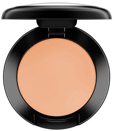 Ein Compact mit pfirsichfarbenem Puder, schwarzer runder Hülse und Spiegel auf dem Deckel.