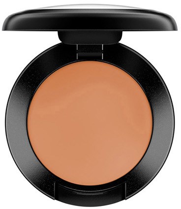 Een ronde compact met oranje poeder en gedeeltelijk open deksel.
