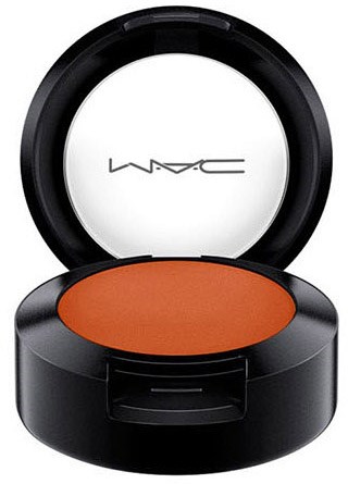 Ein runder Make-up-Presspuder-Container mit offenem Deckel und orangefarbenem Rouge darin.