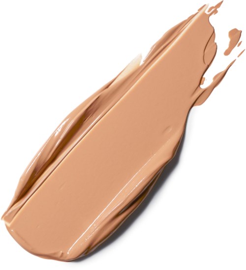 En børste med beige makeupfundament spredt ud på en hvid overflade.