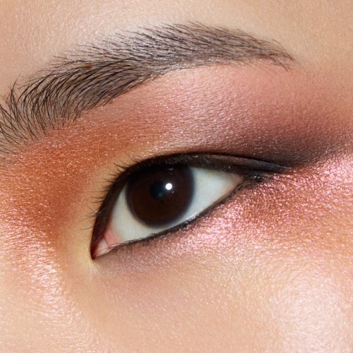 Close-up van iemands oog met make-up, bruin oog en natuurlijke huid. Wenkbrauw zichtbaar boven het oog.