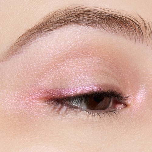 Close-up van een dicht oog met roze glanzende oogschaduw, lange wimpers en goed verzorgde wenkbrauwen.