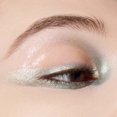 Close-up van iemands oog met glanzende, pastelkleuren make-up en netjes verzorgde wenkbrauwen.