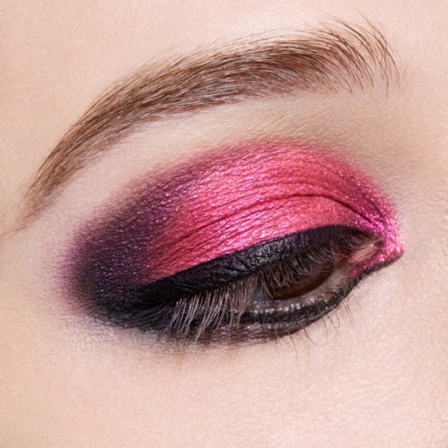 Close-up van oog met opvallende roze en zwarte oogschaduw en goed verzorgde wenkbrouw.