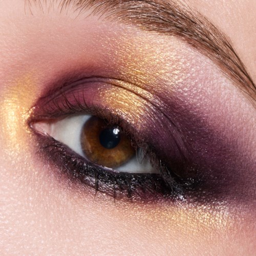 Nærbilde av øyemakeup med gull- og lilla øyenskygge og svart eyeliner.