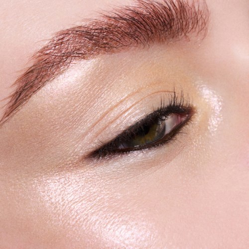 Nærbilde av en persons øye med velpleid øyenbryn, lys øyeskygge og subtil eyeliner.