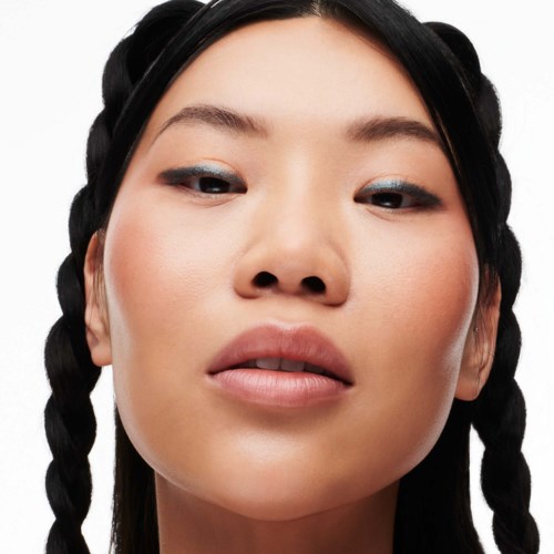 A woman with braided hair, light makeup, and a confident expression looks straight at the camera.