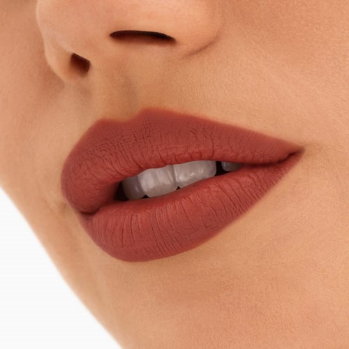 Close-up van lippen met matte lipstick en kleine tanden zichtbaar, deel van een gezicht.