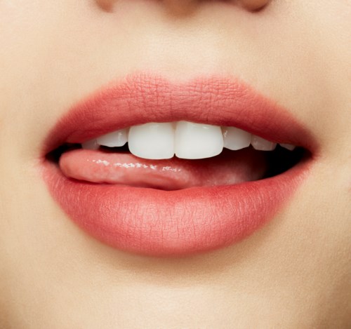 Nahaufnahme der Lippen mit leicht geöffnetem Mund, sichtbare Zähne und herausgestickte Zunge.