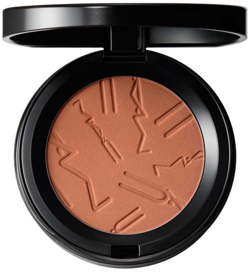 En makeup-kompakt med indgraverede linjer i en ferskenfarvet pudder. Kompaktens låg er sort.