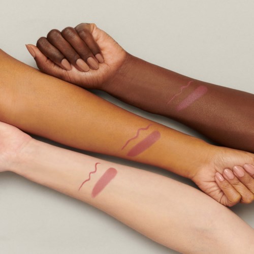 Three arms with different skin tones show swatches of makeup or lipstick colors on forearms.